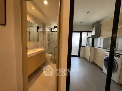 Modern apartment with sleek kitchen and stylish bathroom, featuring wood cabinetry and contemporary appliances.