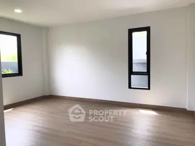 Spacious empty room with large windows and wooden flooring, perfect for customization.