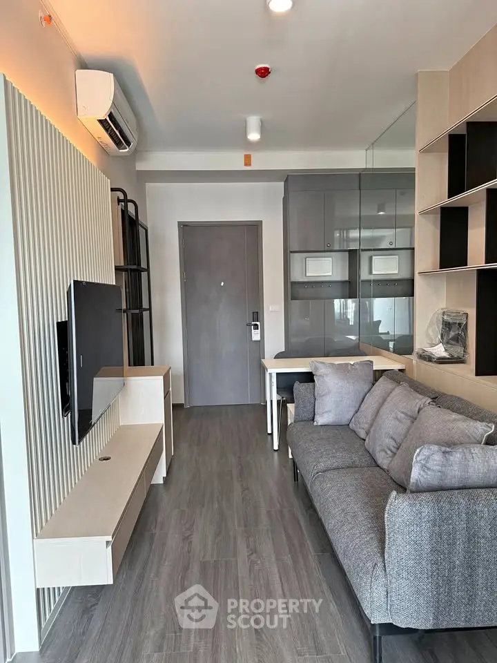 Modern living room with sleek design, featuring a cozy gray sofa, wall-mounted TV, and stylish shelving.