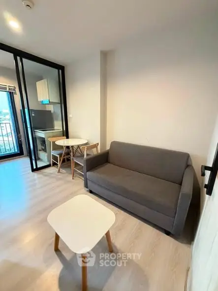 Modern living room with cozy sofa and compact dining area in open layout apartment.