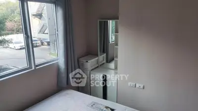 Cozy bedroom with large window and modern furniture in a serene residential area.