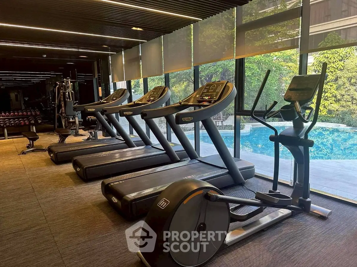 Modern gym with treadmills and pool view in luxury real estate property.
