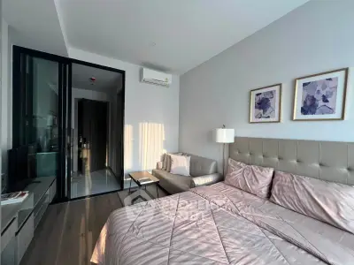 Modern bedroom with stylish decor and natural light, featuring a cozy bed and elegant artwork.