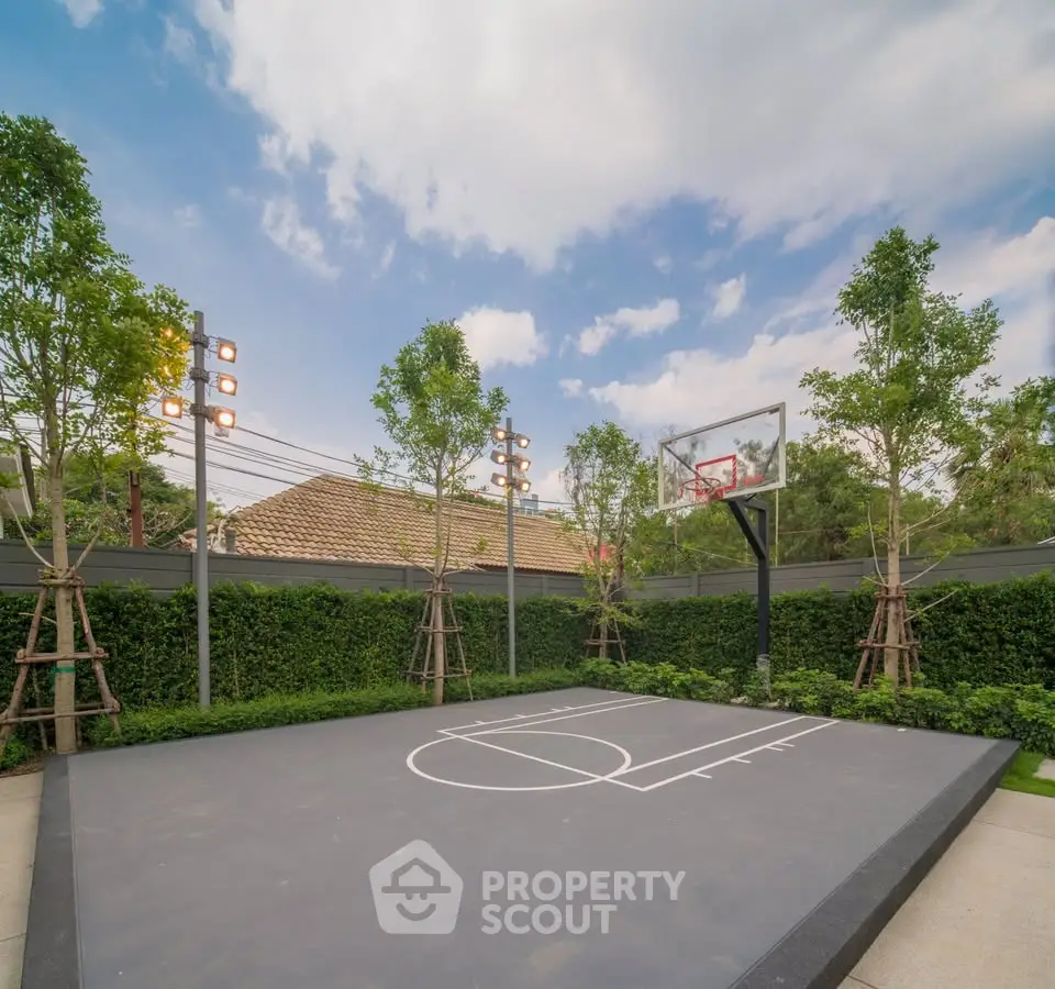 Luxurious outdoor basketball court with lush greenery and modern lighting in a serene residential setting.