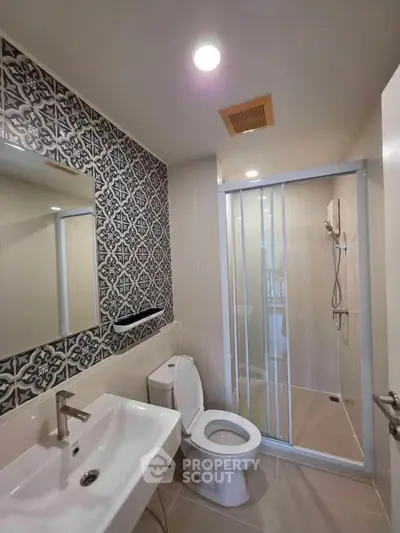 Modern bathroom with stylish tile accent wall and glass shower enclosure.