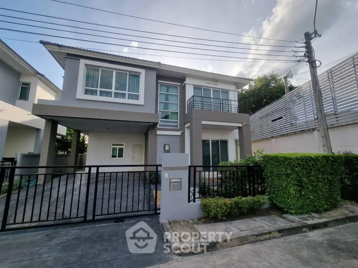 Modern two-story house with sleek design and gated driveway in suburban neighborhood.
