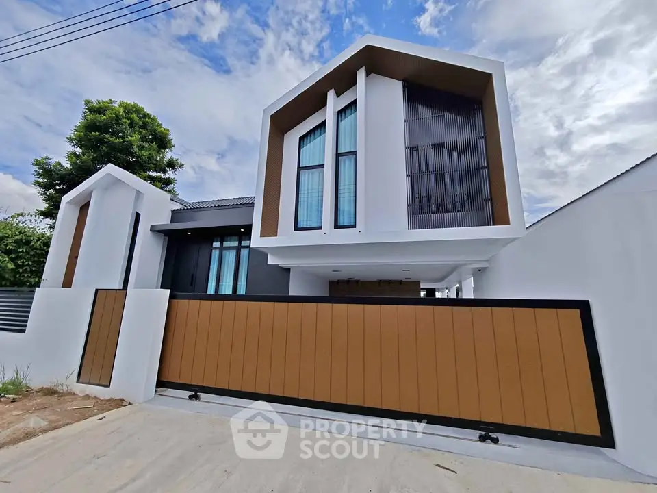 Modern two-story house with unique architectural design and large wooden gate.