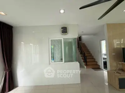 Spacious modern living area with staircase and large windows, ideal for natural light and open living.