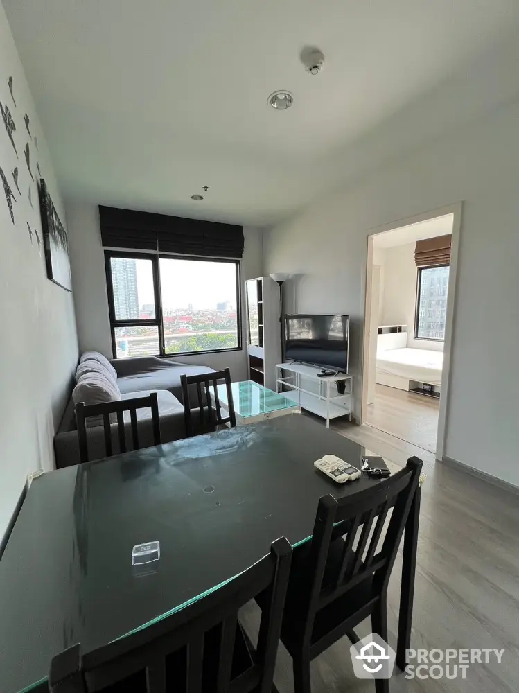 Modern living room with dining area and city view, featuring sleek furniture and large windows.