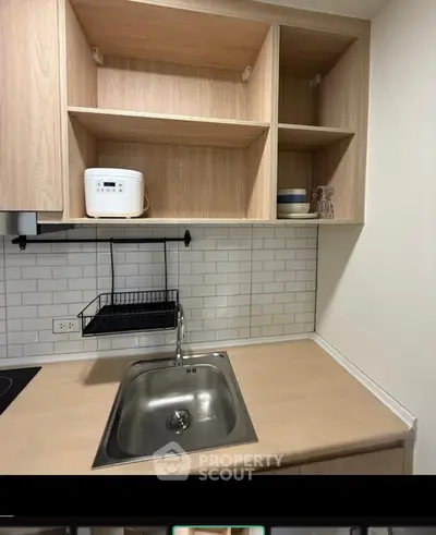 Modern kitchen with sleek sink and open shelving, perfect for compact living spaces.