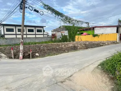 Vacant land plot on a corner lot with potential for development, surrounded by urban buildings.