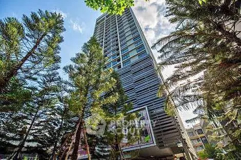 Stunning modern high-rise building surrounded by lush trees and vibrant cityscape.