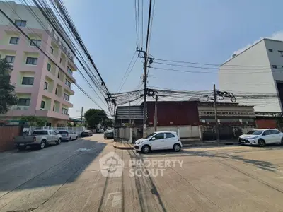 Urban street view with residential buildings and parked cars under clear blue sky.
