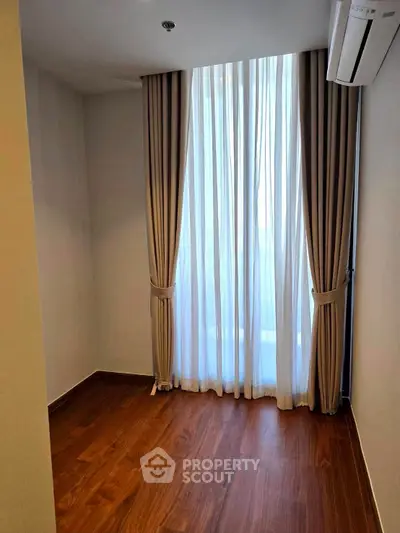 Cozy room with elegant curtains and wooden flooring, perfect for a serene living space.