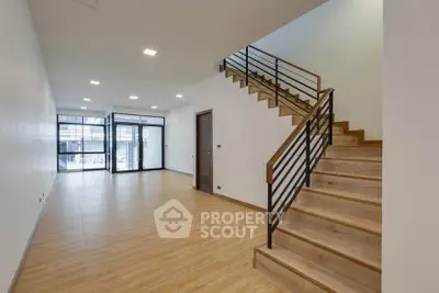 Spacious modern living room with wooden flooring and stylish staircase, perfect for contemporary living.