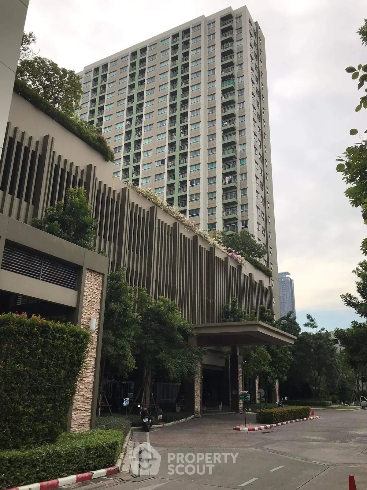 Modern high-rise building with lush greenery and elegant facade in urban setting.