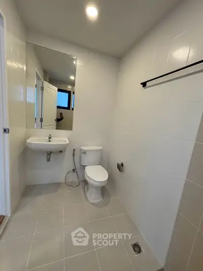 Modern bathroom with sleek fixtures and neutral tiles, featuring a wall-mounted sink and toilet.