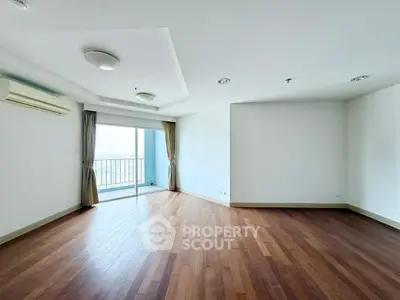 Spacious empty living room with wooden floors and balcony view