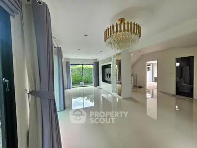 Spacious modern living room with elegant chandelier and large windows.