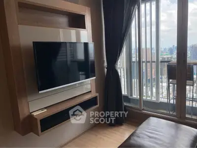 Modern living room with wall-mounted TV and stunning city view from balcony.
