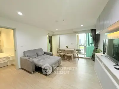 Modern living room with gray sofa, dining area, and balcony view in stylish apartment.