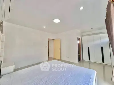 Spacious minimalist bedroom with modern wardrobe and ample natural light.