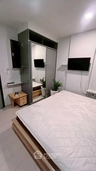 Modern bedroom with mirrored wardrobe and mounted TV, perfect for urban living.