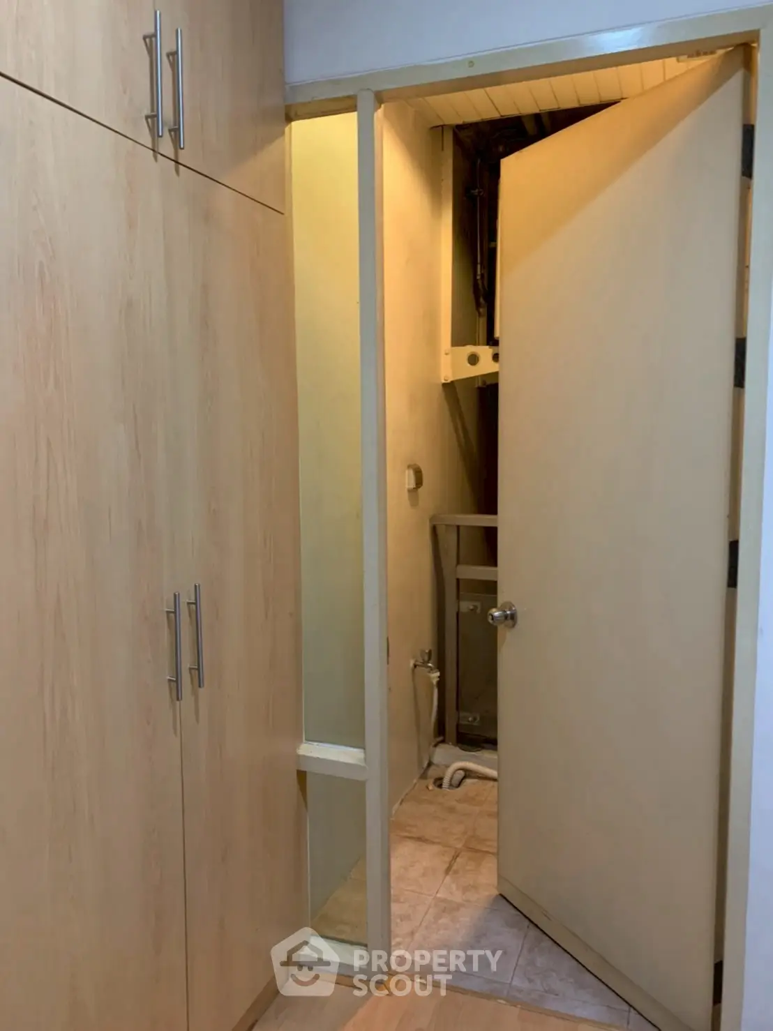 Compact storage space with wooden cabinets and open door