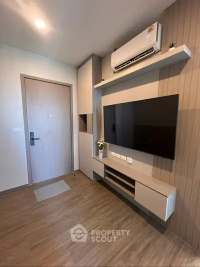 Modern living room with wall-mounted TV and air conditioning unit, featuring sleek wooden flooring and stylish decor.
