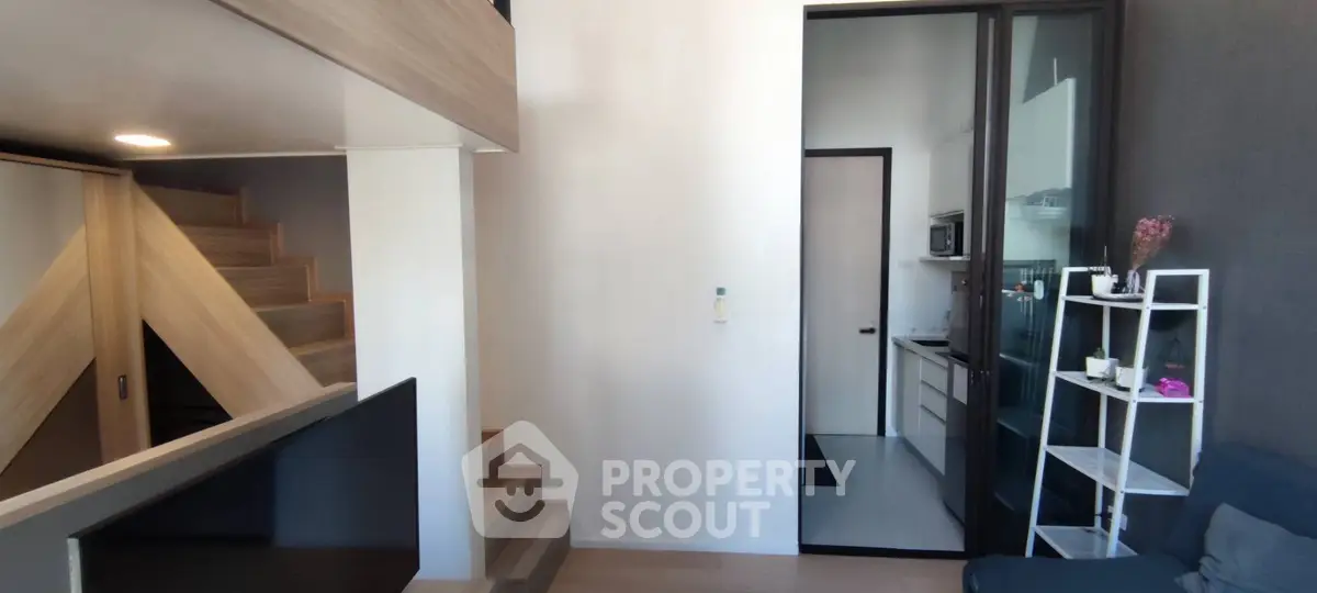 Modern loft apartment with stylish staircase and compact kitchen area, perfect for urban living.