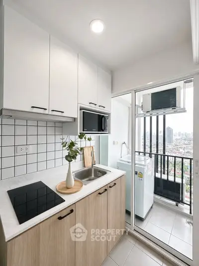 Modern kitchen with sleek appliances and balcony view in urban apartment