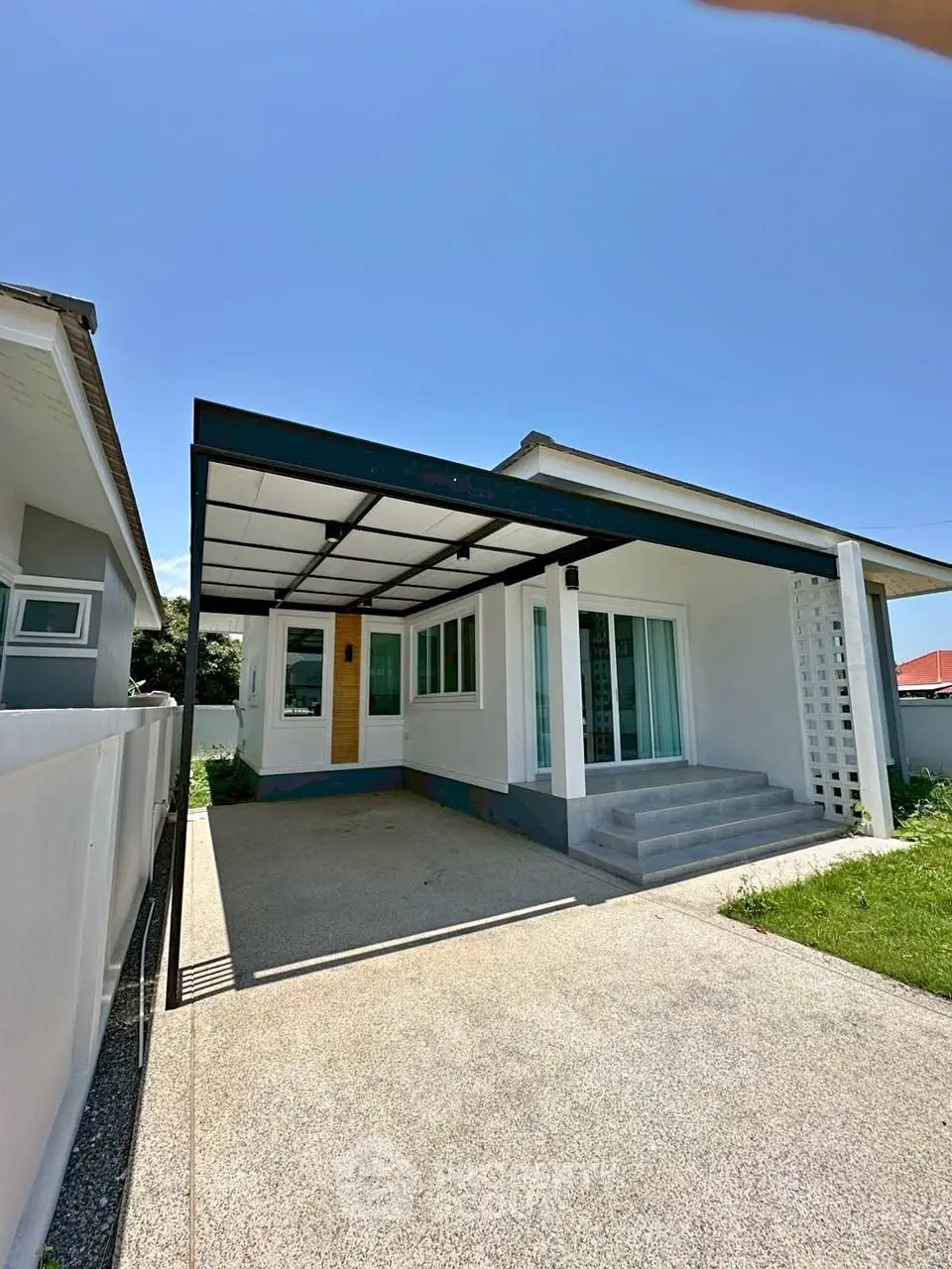 Charming modern house with covered carport and lush green lawn under clear blue sky.