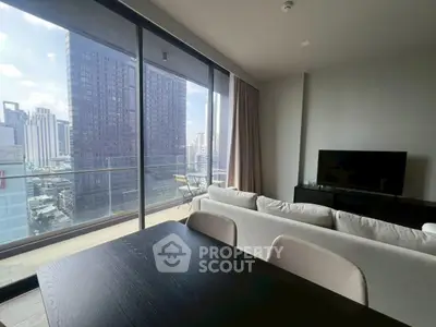 Modern living room with large windows and city view, featuring a cozy sofa and sleek TV setup.