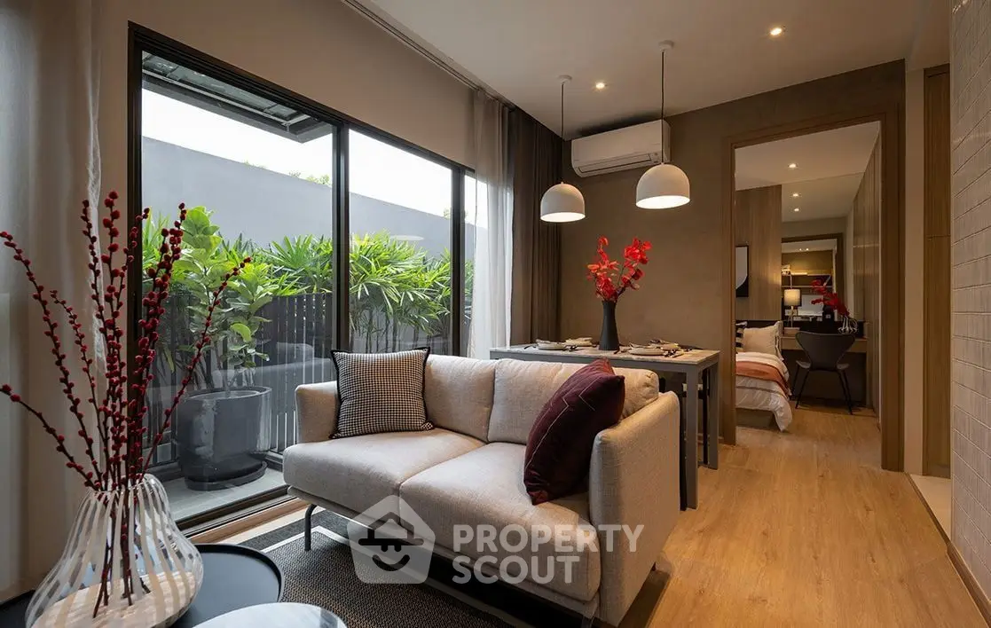 Modern living room with stylish decor and large window overlooking lush greenery.