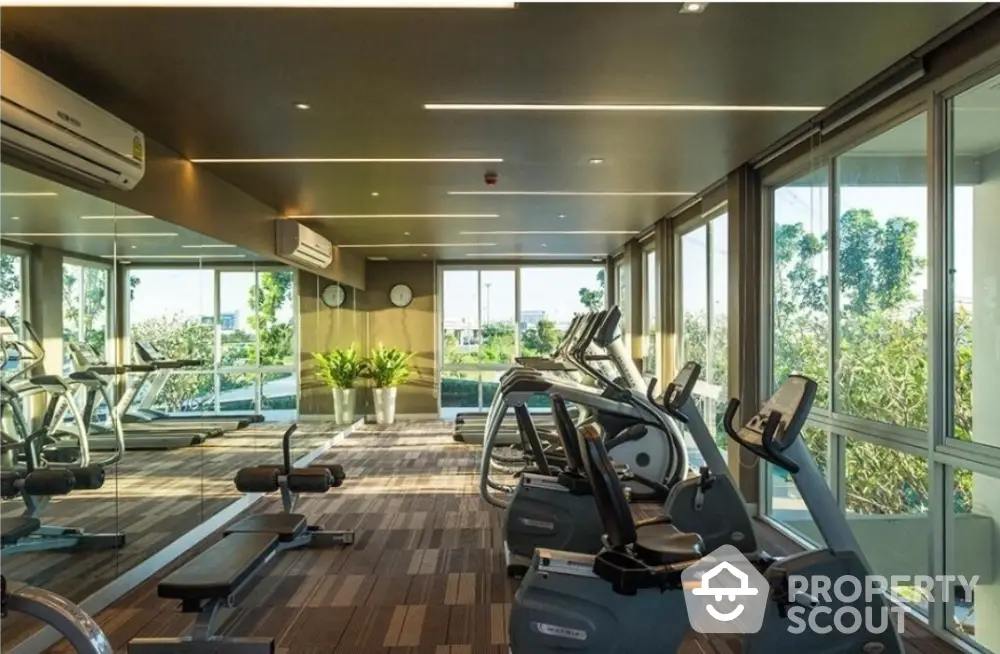 Modern gym with large windows and fitness equipment in a luxury apartment building.