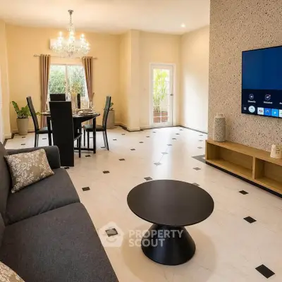 Elegant living room with modern decor and dining area, featuring a stylish chandelier and wall-mounted TV.