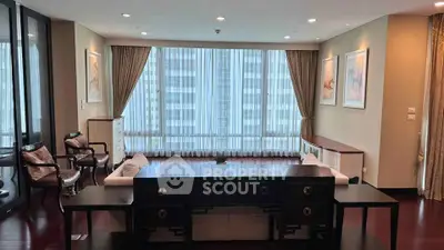 Spacious living room with elegant decor and large windows offering city views.