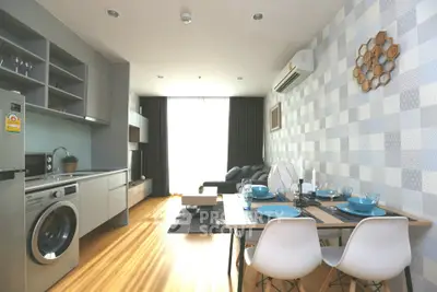 Modern living room with open kitchen, stylish decor, and natural light.