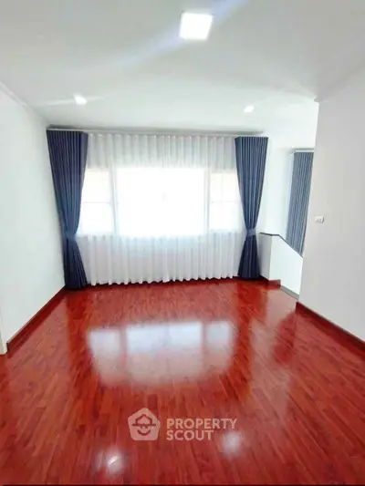 Spacious room with polished wooden floors and elegant curtains, perfect for a cozy living space.