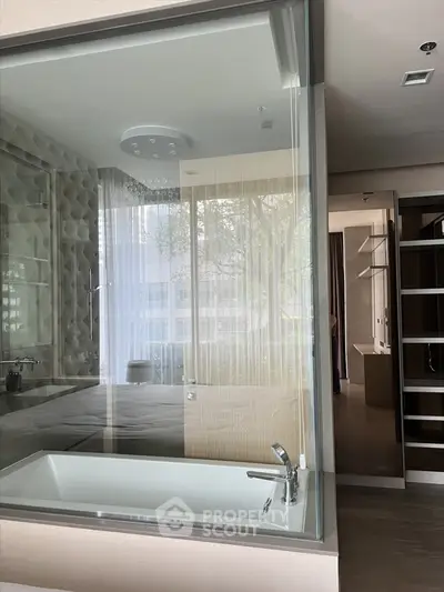 Luxurious modern bathroom with glass partition and sleek bathtub in upscale apartment.