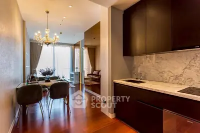 Luxurious open-plan kitchen and dining area with elegant chandelier and modern decor.