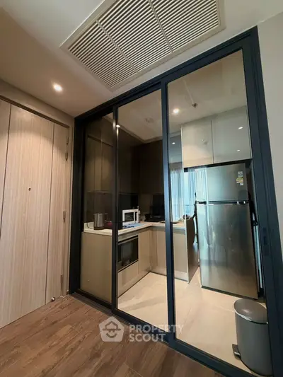 Modern kitchen with sleek appliances and glass sliding doors in a stylish apartment.