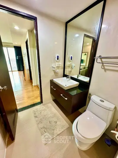 Modern bathroom with sleek fixtures and a view into a bright living area.