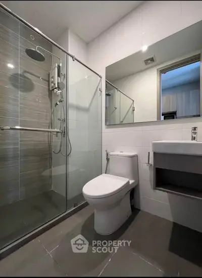Modern bathroom with glass shower and sleek fixtures in contemporary apartment.