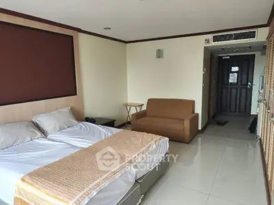 Spacious bedroom with modern decor and cozy seating area in a well-lit apartment.