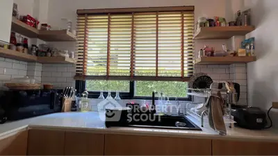 Charming kitchen with modern appliances and ample shelving, featuring a window with wooden blinds and a sleek sink.