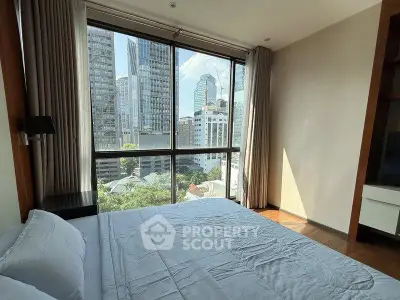 Luxurious bedroom with stunning city view from large windows in modern high-rise apartment.