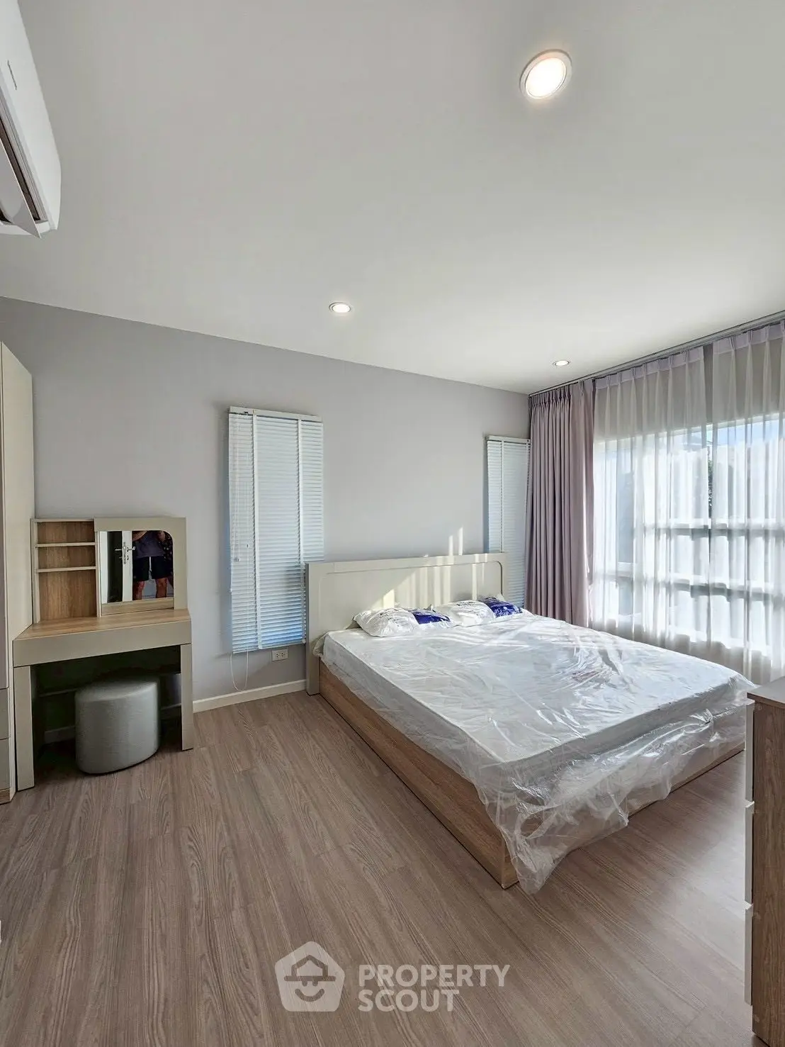 Spacious bedroom with natural light and modern furnishings in a stylish apartment.