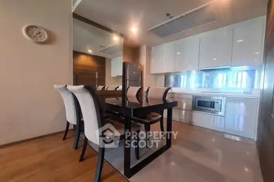 Modern kitchen with dining area, sleek cabinetry, and stainless steel appliances in a stylish apartment.