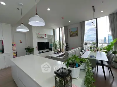 Spacious modern living room with open kitchen and city view, featuring stylish decor and ample natural light.